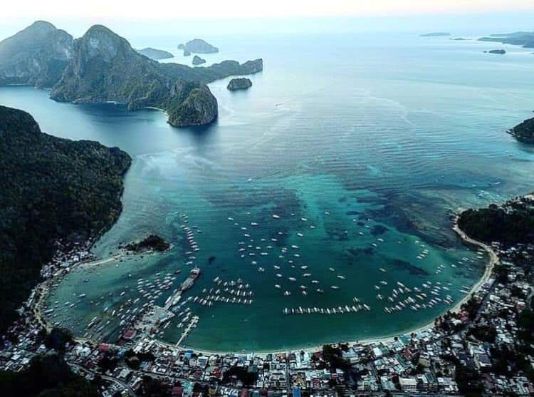 El Nido town and its boat-filled bay from above, with karst islands beyond